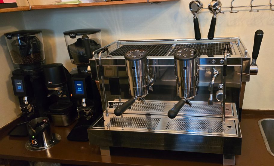 Siebträgermaschine Moderne Espressomaschine mit zwei Brühgruppen und daneben Kaffeemühlen.
