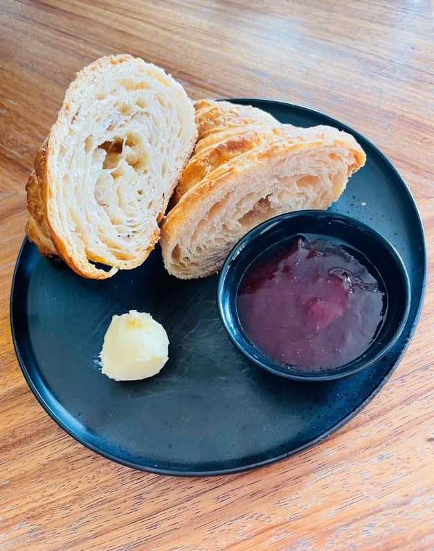 Continental Breakfast Zwei Stücke Brot mit einer Beilage aus Konfitüre und einem Klecks Butter.